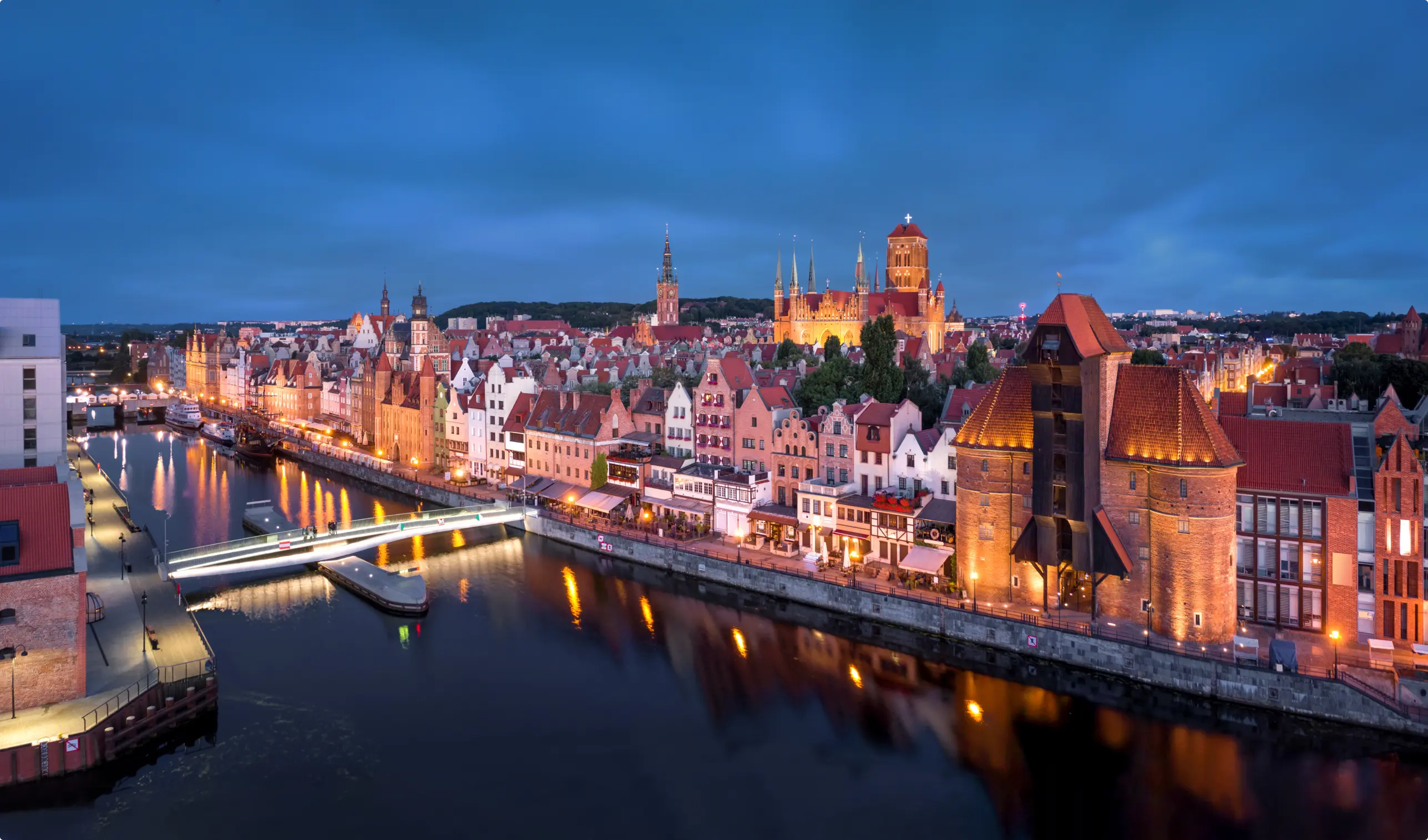 Wieczorna panorama Gdańska z widokiem na zabytkowe budynki, kamienice i most