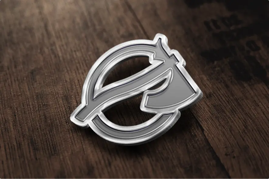 Srebrna przypinka z logo Baldur na drewnianym blacie, logo stworzone przez software house Kryptonum