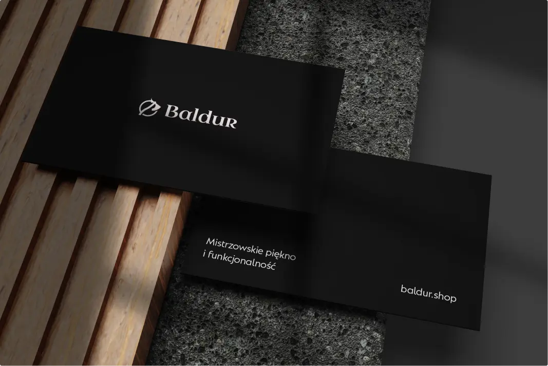 Projekt czarnych wizytówek z logo Baldur na kamienno-drewnianym tle. Wizytówki stworzone przez agencję interaktywną Kryptonum